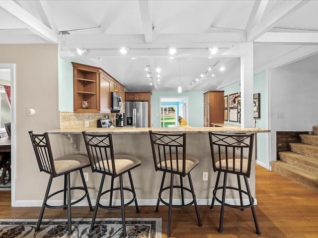 kitchen featuring open shelves, lofted ceiling with beams, a peninsula, stainless steel appliances, and brown cabinets