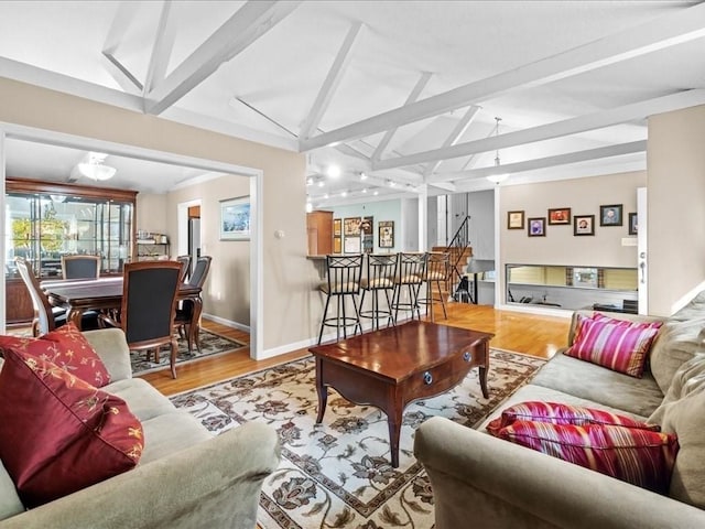 living area with lofted ceiling with beams, baseboards, and wood finished floors