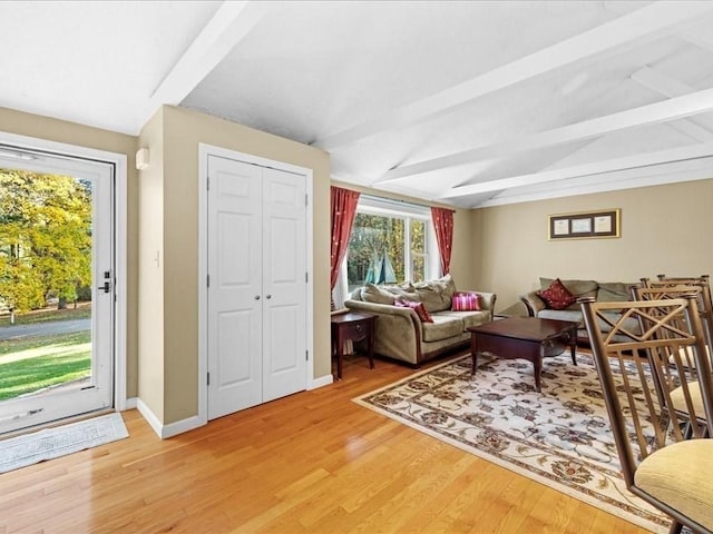 living area with vaulted ceiling with beams, light wood-type flooring, and baseboards