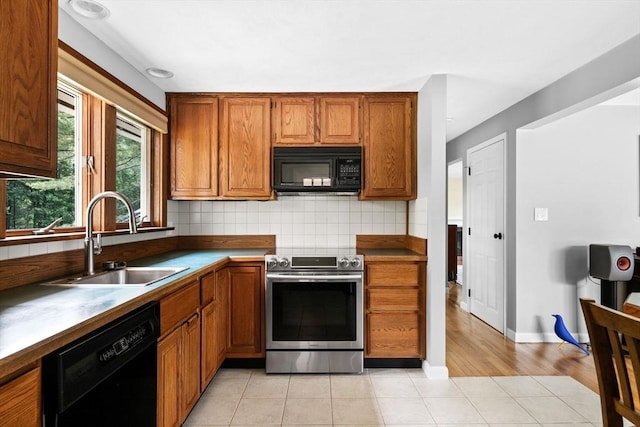 42 Howe St, Ipswich, MA 01938 - kitchen with black appliances, a sink, backsplash, brown cabinetry, and light tile patterned floors