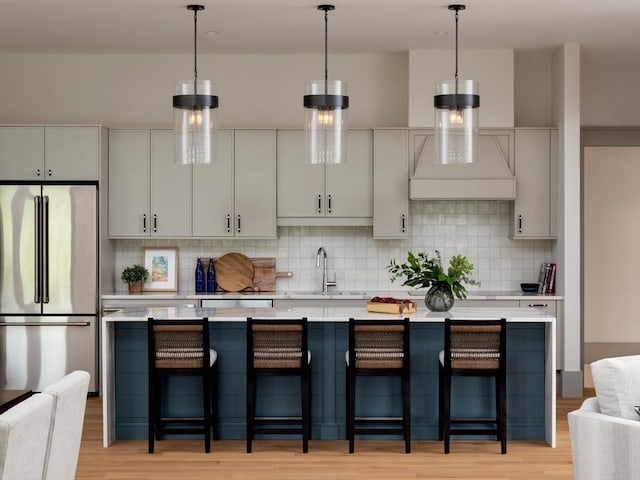 kitchen featuring stainless steel refrigerator, a kitchen breakfast bar, sink, and hanging light fixtures