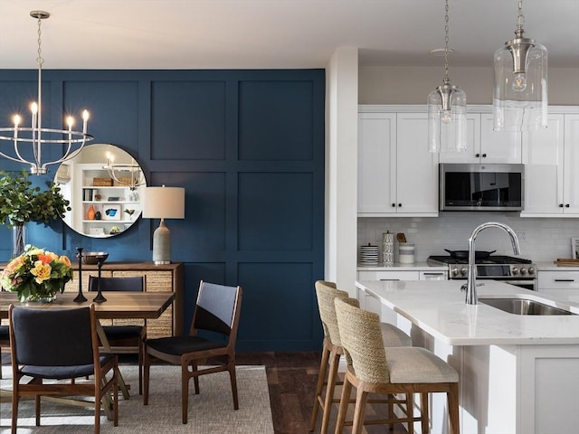 kitchen with white cabinetry, appliances with stainless steel finishes, backsplash, and pendant lighting