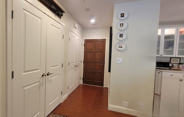 corridor featuring baseboards and dark wood finished floors
