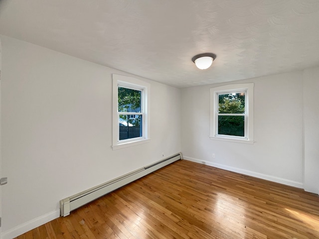 unfurnished room with a baseboard heating unit, hardwood / wood-style floors, and a textured ceiling