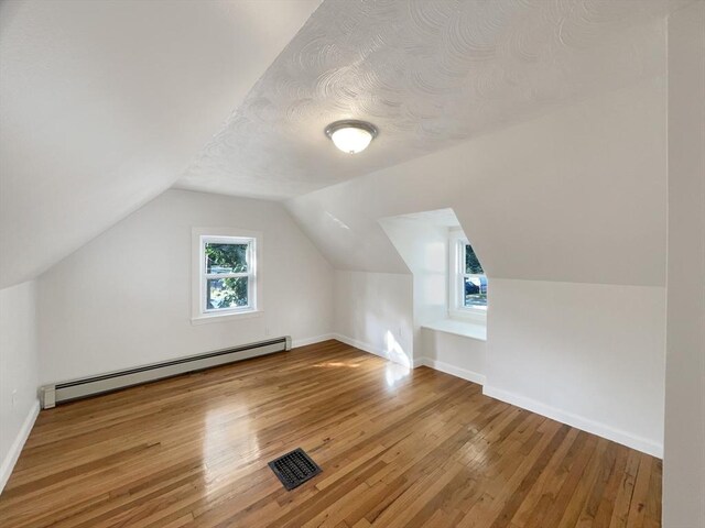 444 Lowell St, Reading, MA 01867 - additional living space with a baseboard radiator, hardwood / wood-style flooring, lofted ceiling, and baseboards