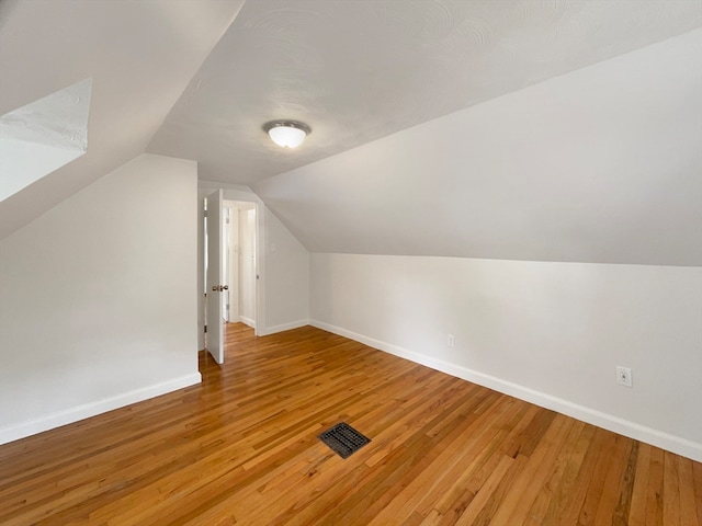 additional living space with hardwood / wood-style flooring and vaulted ceiling