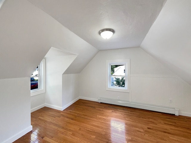 additional living space featuring wood-type flooring, baseboard heating, and vaulted ceiling