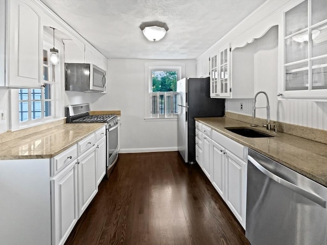 444 Lowell St, Reading, MA 01867 - kitchen with stainless steel appliances, a sink, glass insert cabinets, white cabinetry, and dark wood-type flooring