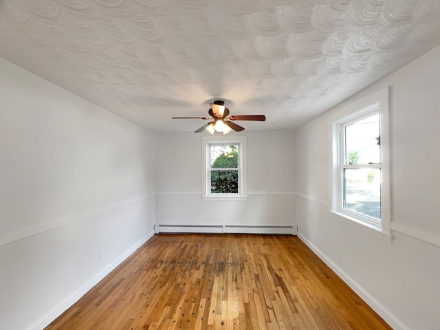 empty room with a textured ceiling, baseboard heating, light hardwood / wood-style flooring, and ceiling fan