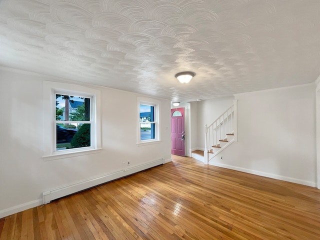 interior space featuring light wood-type flooring, a textured ceiling, and a baseboard radiator