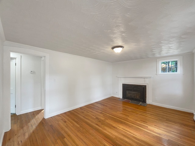 unfurnished living room with hardwood / wood-style flooring, a textured ceiling, and ornamental molding