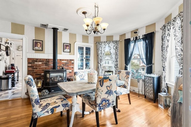 dining room with light wood finished floors, a wood stove, and a chandelier