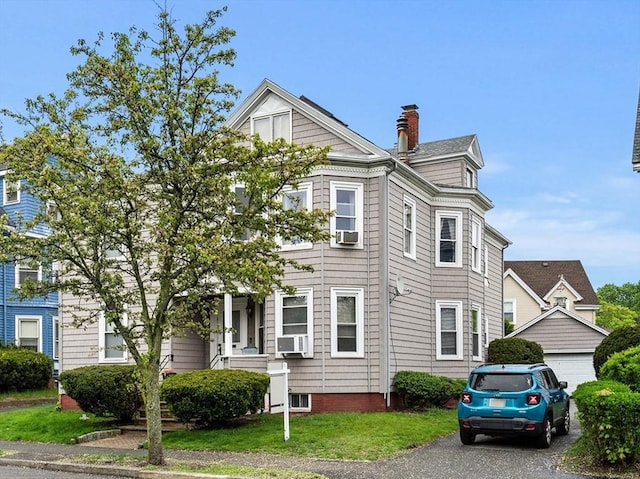 view of front of home with a garage, cooling unit, and a chimney