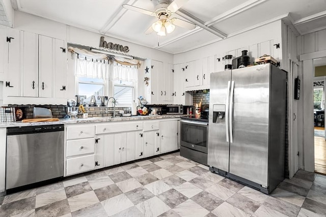 kitchen featuring appliances with stainless steel finishes, a sink, ceiling fan, tasteful backsplash, and light countertops