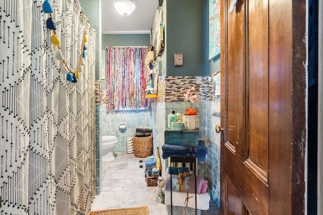 full bathroom featuring tile walls, toilet, wainscoting, a shower with shower curtain, and tile patterned floors