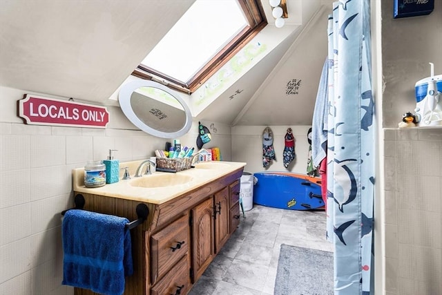 full bath featuring a skylight, lofted ceiling, double vanity, and curtained shower