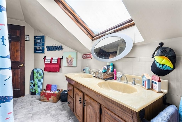 bathroom with vaulted ceiling, double vanity, and a skylight