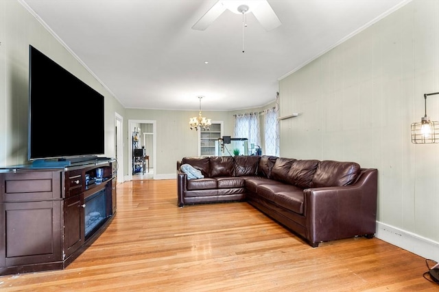 living area with a chandelier, light wood-style flooring, baseboards, and ornamental molding