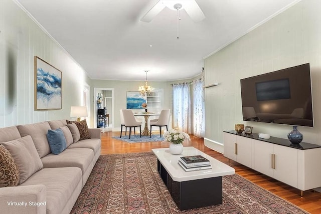 living room with ornamental molding, wood finished floors, a chandelier, and a ceiling fan