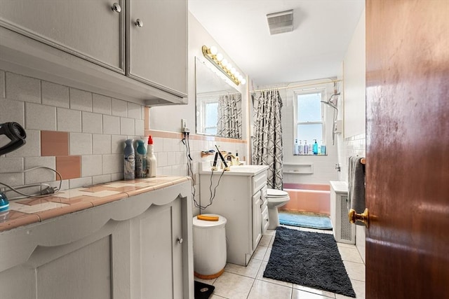 bathroom with toilet, tile patterned flooring, shower / tub combo with curtain, vanity, and tasteful backsplash