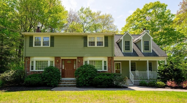 7 Harold Ave, Wilmington, MA 01887 - view of front of home with a chimney, brick siding, a front lawn, and covered porch
