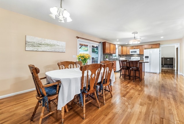 dining space with light hardwood / wood-style floors, an inviting chandelier, and sink