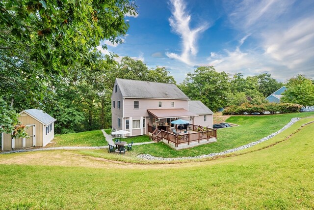 rear view of house featuring a storage shed, a yard, and a wooden deck