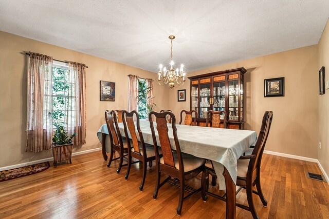 dining space featuring an inviting chandelier, a textured ceiling, and hardwood / wood-style floors