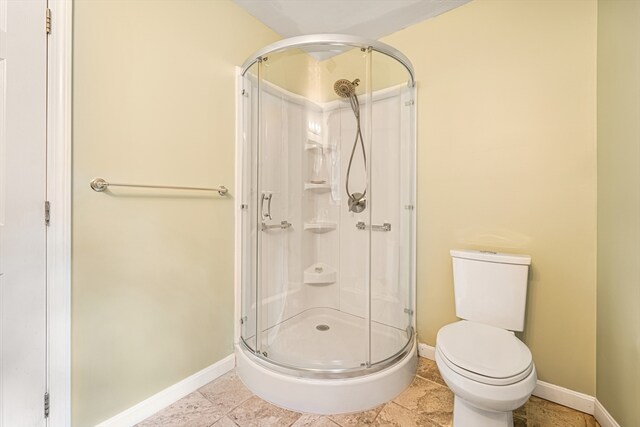 bathroom featuring a shower with door, toilet, and tile patterned floors