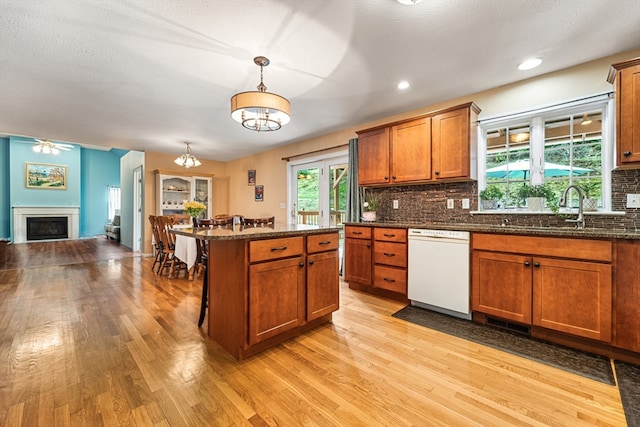 kitchen featuring white dishwasher, light hardwood / wood-style flooring, hanging light fixtures, and a breakfast bar