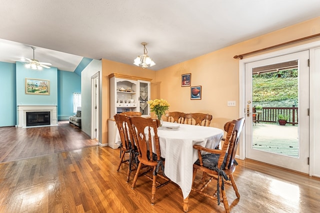 dining area with wood-type flooring, ceiling fan with notable chandelier, and vaulted ceiling