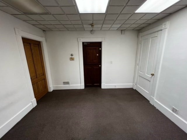 carpeted spare room with a drop ceiling