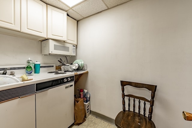 kitchen with a paneled ceiling and white cabinetry