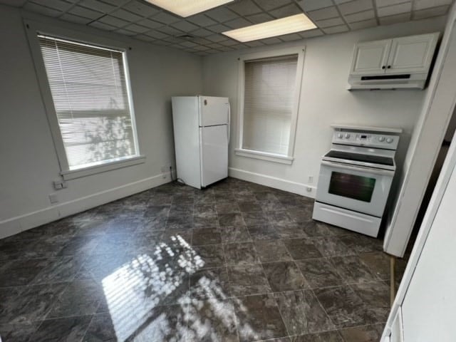 kitchen with white appliances, white cabinetry, and a paneled ceiling