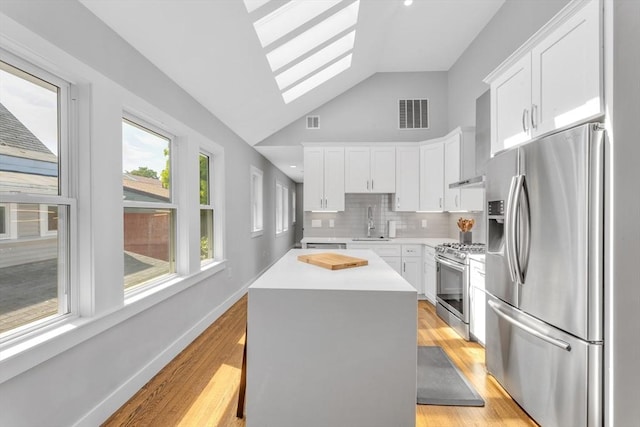 72 Rawson Rd Unit 2, Arlington, MA 02474 - kitchen with stainless steel appliances, a skylight, lofted ceiling, white cabinetry, and light countertops