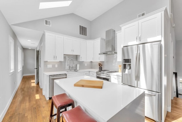 72 Rawson Rd Unit 2, Arlington, MA 02474 - kitchen featuring appliances with stainless steel finishes, wall chimney range hood, a sink, a skylight, and backsplash