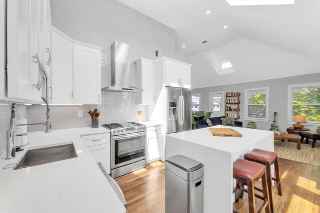 72 Rawson Rd Unit 2, Arlington, MA 02474 - kitchen with appliances with stainless steel finishes, wall chimney exhaust hood, a sink, light wood-style flooring, and lofted ceiling