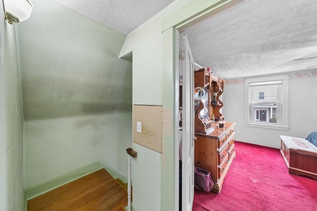 hall featuring a textured ceiling and baseboards