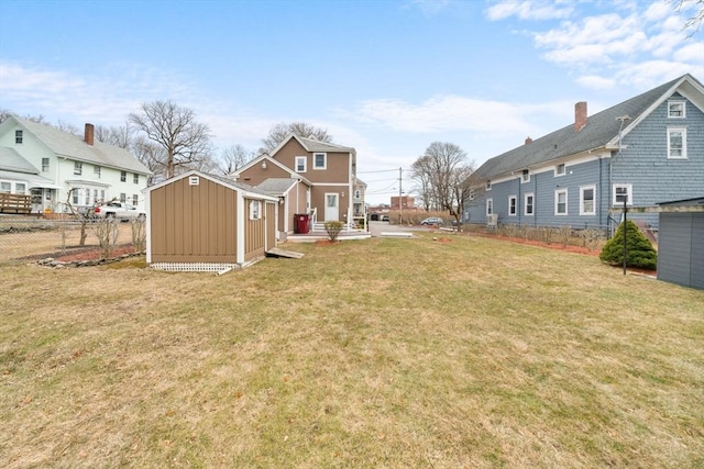 view of yard with a shed, a residential view, fence, and an outbuilding