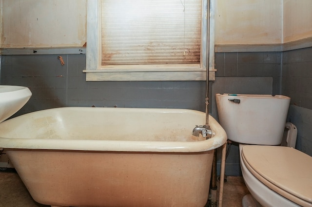 bathroom with toilet, a bathtub, and tile walls