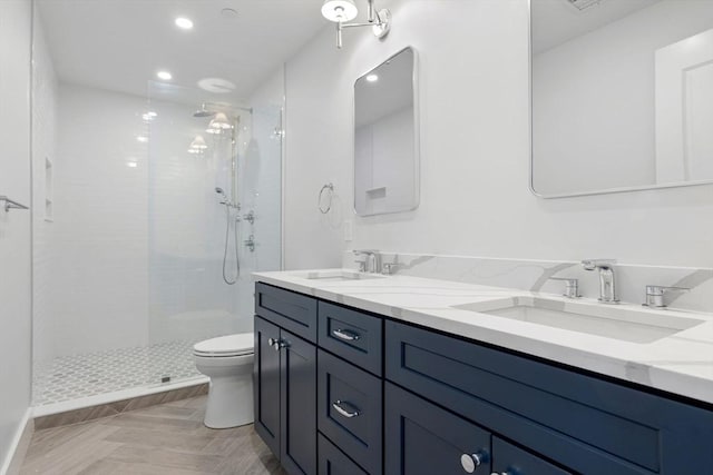 bathroom with tiled shower, vanity, and toilet