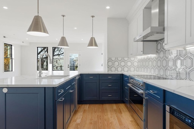 kitchen with decorative light fixtures, decorative backsplash, wall chimney range hood, and blue cabinets