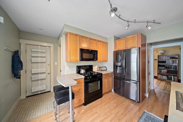 149 Milton Ave, Boston, MA 02124 - kitchen with black appliances, light countertops, backsplash, light wood finished floors, and baseboards