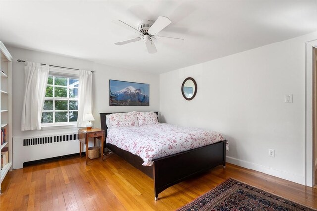 bedroom featuring radiator heating unit, baseboards, ceiling fan, and wood-type flooring