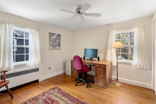 office with baseboards, ceiling fan, radiator heating unit, and light wood-style floors