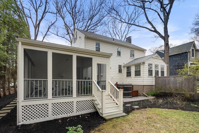 rear view of property with fence, a chimney, a jacuzzi, and a sunroom