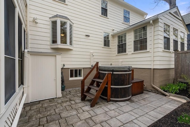 back of house with a hot tub and a patio