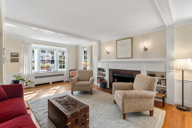 living area featuring crown molding, radiator heating unit, hardwood / wood-style flooring, and a fireplace