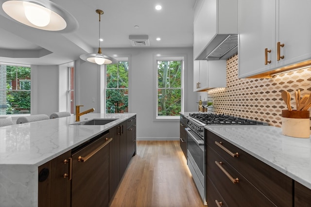 kitchen with light hardwood / wood-style flooring, sink, white cabinetry, appliances with stainless steel finishes, and tasteful backsplash