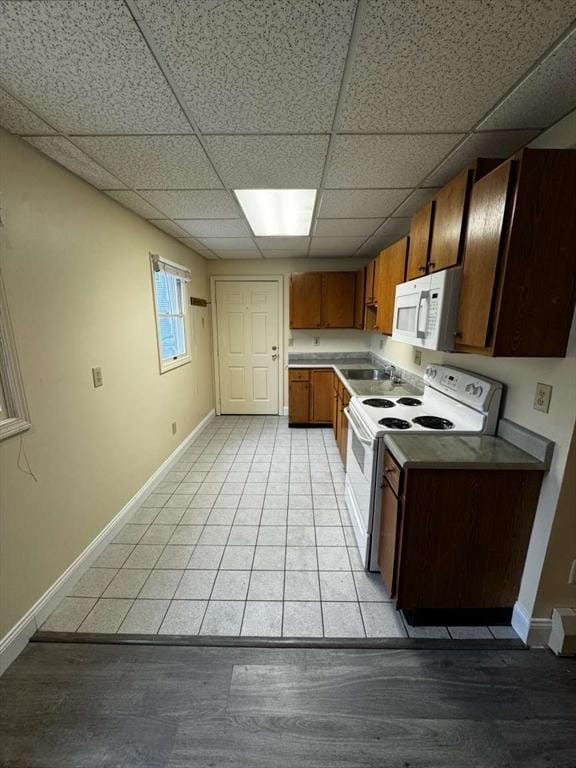 kitchen featuring light tile patterned floors, white appliances, a paneled ceiling, and sink